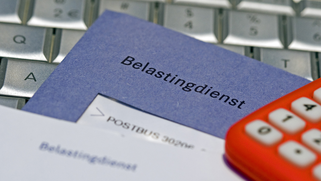 Envelop van de Belastingdienst op een toetsenbord naast een rekenmachine